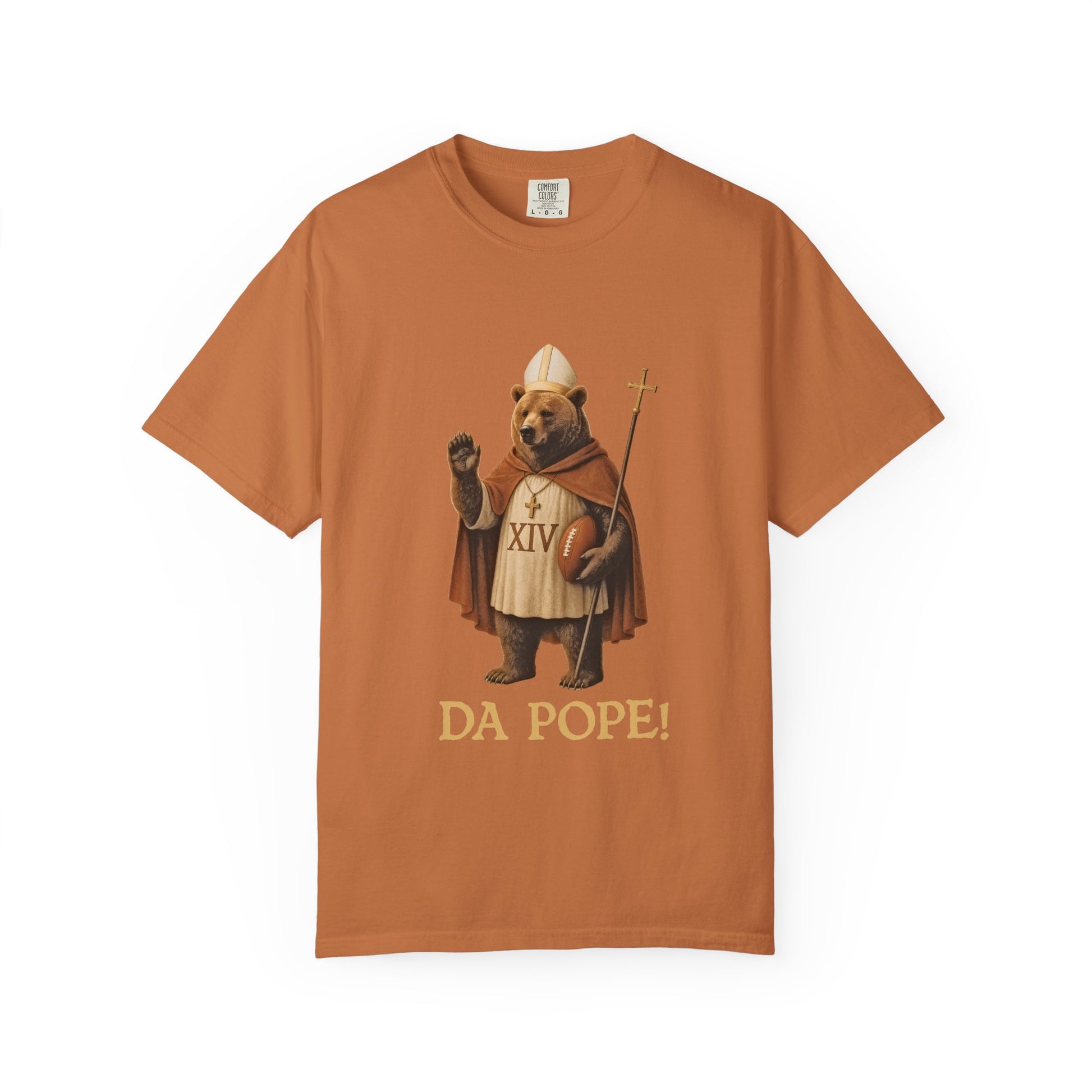 The front side of a burnt orange colored t shirt with a design of a Bear dressed as the pope with the saying DA POPE! below.