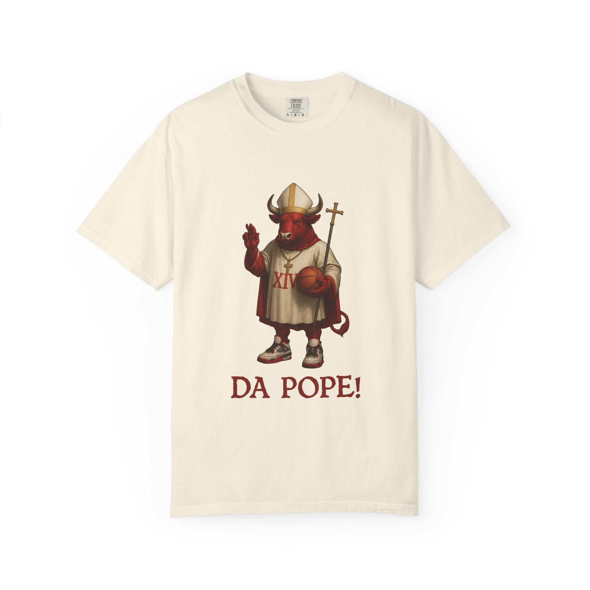 The front side of a ivory colored t shirt with a design of a red Bull dressed as the pope with the saying DA POPE! below.
